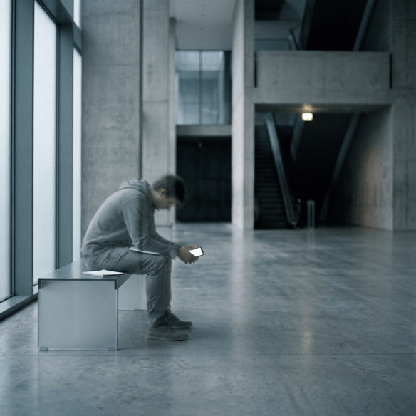 Person sitting on bench in modern lobby looking at phone